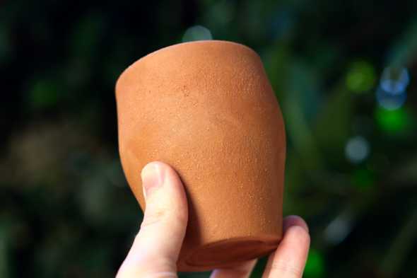 A hand holding an unfired mug.